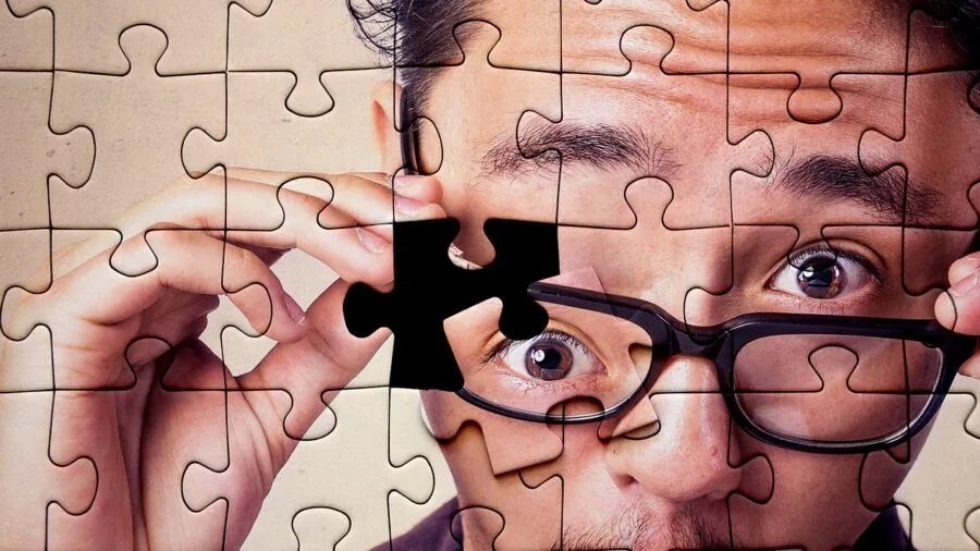 Person concentrating while working on a jigsaw puzzle at home table