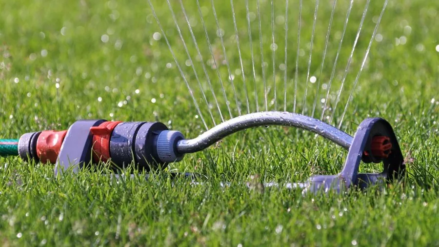 Person connecting garden hose to RV water hookup at campground spigot