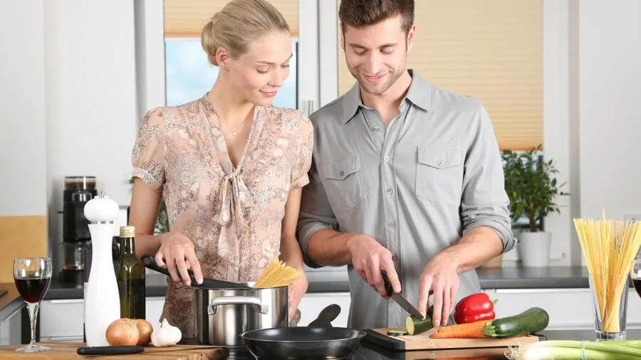 Person cooking with essential cookware in a bright, modern kitchen during daily meal preparation