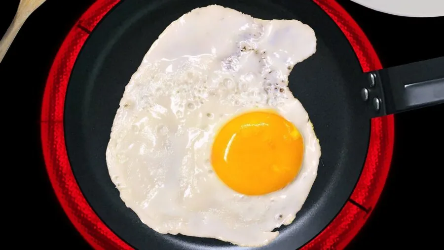 Person cooking with pan on modern induction cooktop in home kitchen