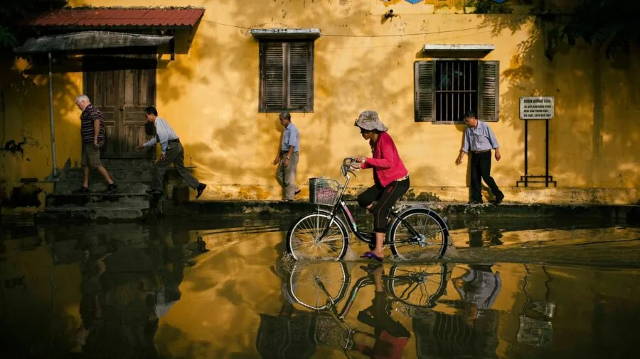 Person cycling through rainy weather conditions on city street, demonstrating bike durability in wet conditions