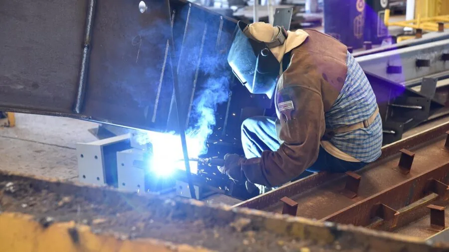Person demonstrating proper lifting technique with heavy industrial materials in warehouse setting