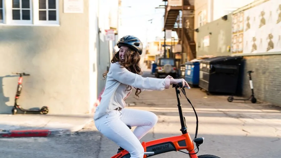 Person demonstrating quick folding mechanism on portable bike in urban setting