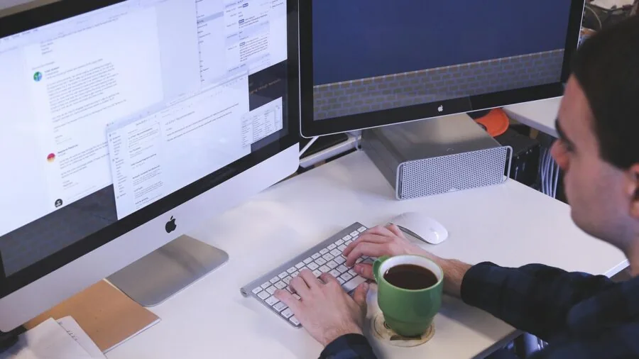 Person effortlessly adjusting computer monitor height at standing desk in bright home office workspace