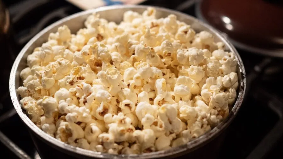 Person enjoying a bowl of freshly popped popcorn as a healthy snack at home