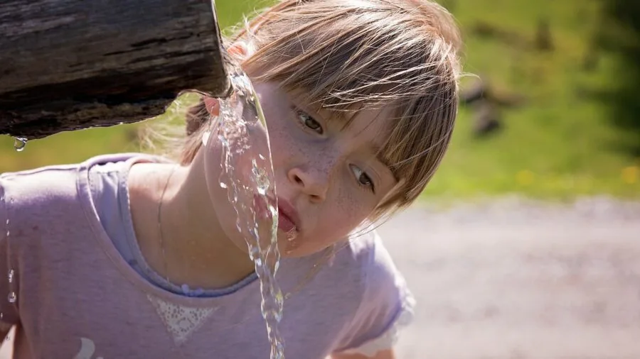 Person enjoying a cold beverage during outdoor activity, demonstrating temperature retention in insulated bottles