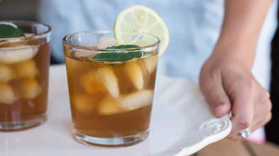 Person enjoying a cold beverage with ice cubes on a warm day