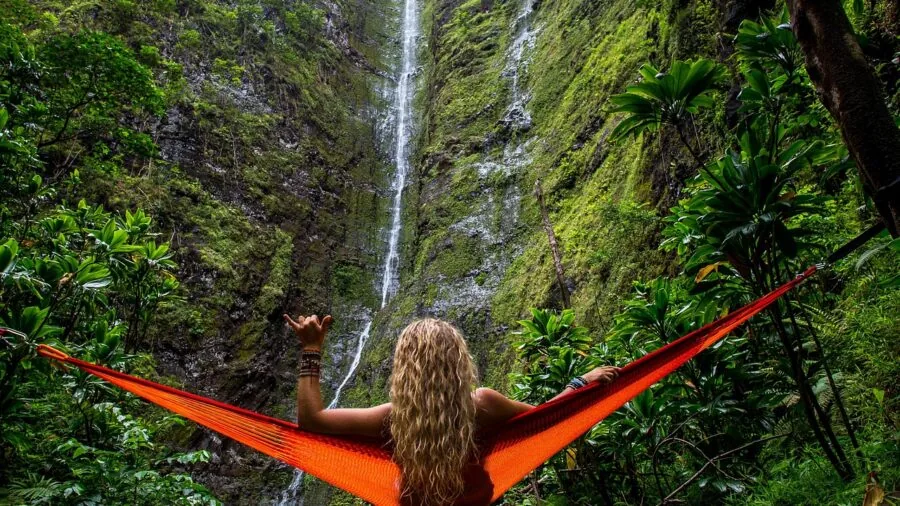 Person enjoying a hammock in a natural outdoor setting surrounded by trees and greenery