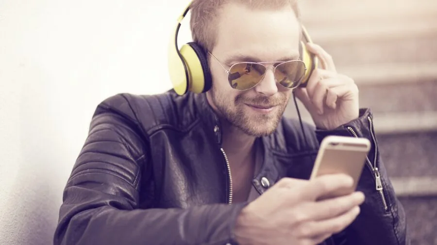 Person enjoying audiobook on smartphone during daily commute with earbuds