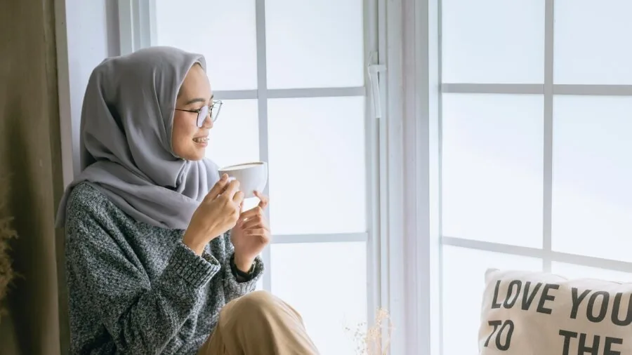 Person enjoying morning coffee in natural light, depicting daily beverage habits that stain teeth and dentures