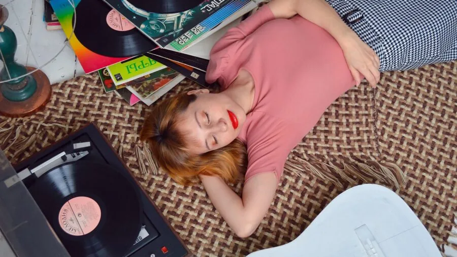 Person enjoying music on a vintage turntable in a cozy home setting with vinyl records