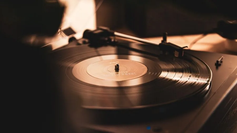 Person enjoying music outdoors with vinyl records and listening setup in natural daylight setting