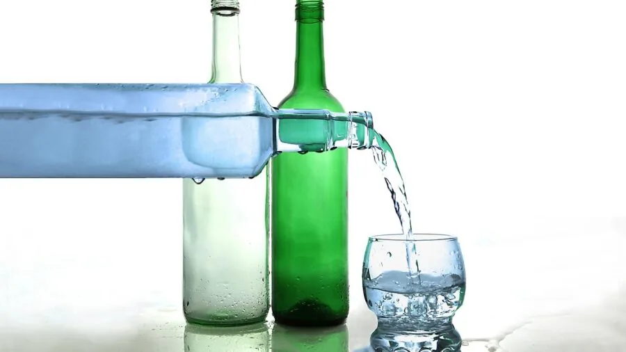 Person examining and comparing different water bottle options on a table, evaluating choices