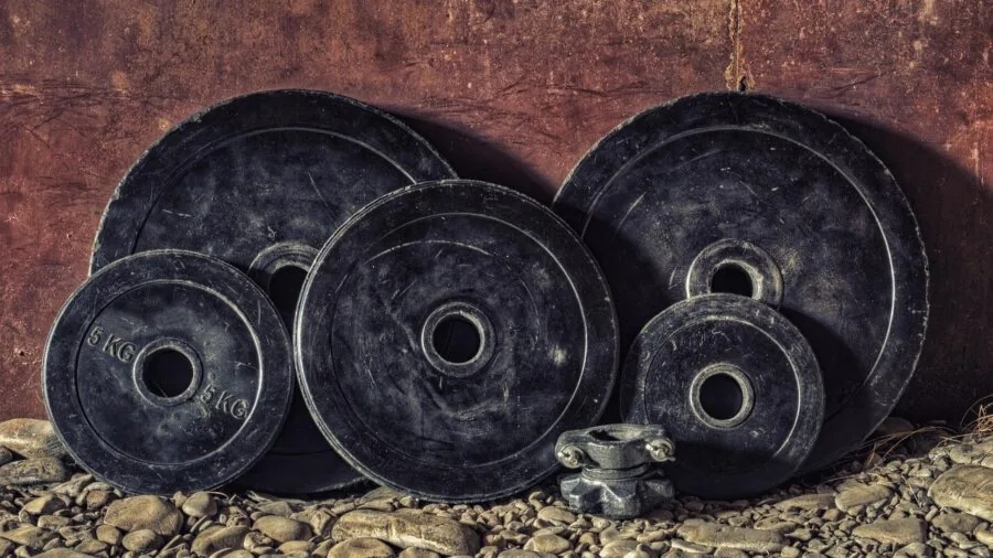 Person examining barbell sleeves and gym equipment in home workout space