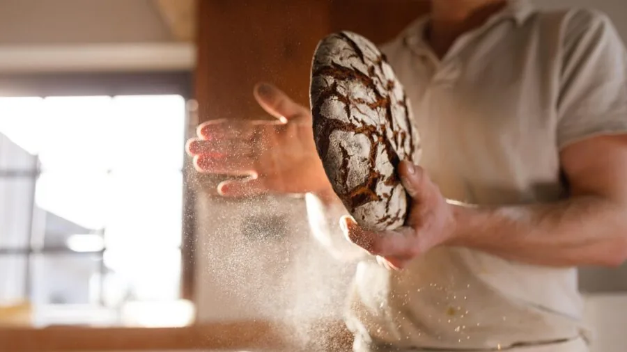 Person examining different baking pans and kitchen tools while budgeting for home baking supplies