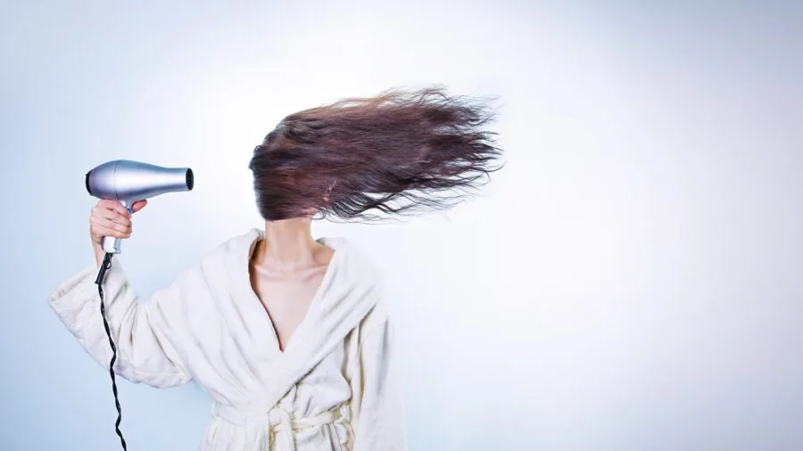 Person examining different hair conditioner bottles while making purchasing decision in bathroom
