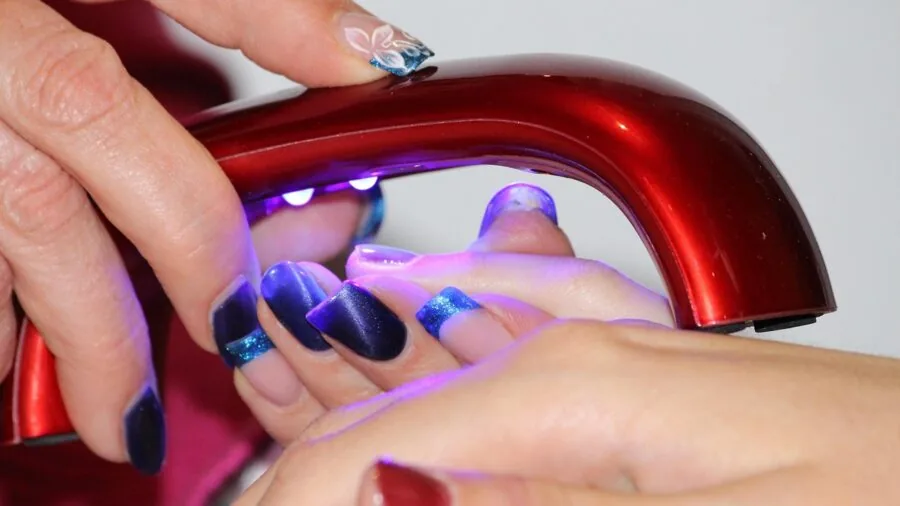 Person examining freshly painted nails waiting for polish to dry, demonstrating quick-dry performance