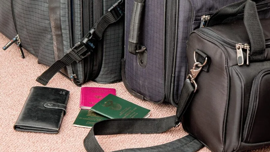 Person examining luggage zipper detail during travel preparation, checking bag quality and durability