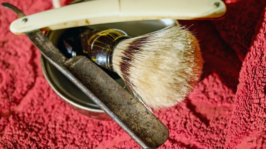 Person examining razor blades in bathroom mirror during morning grooming routine