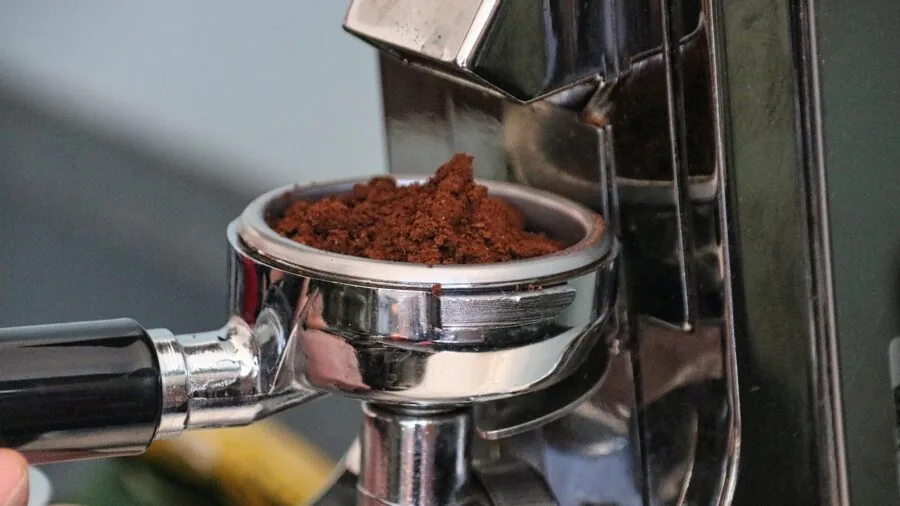 Person examining two different coffee grinder types side by side on kitchen counter