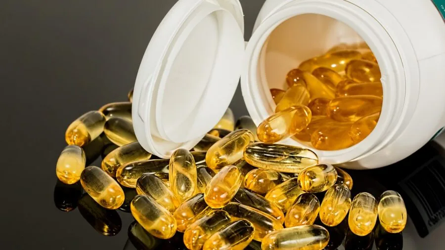 Person examining vitamin supplement dosage information on bottle label in natural lighting