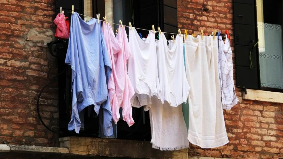 Person examining white deodorant residue stain on dark shirt fabric during laundry inspection