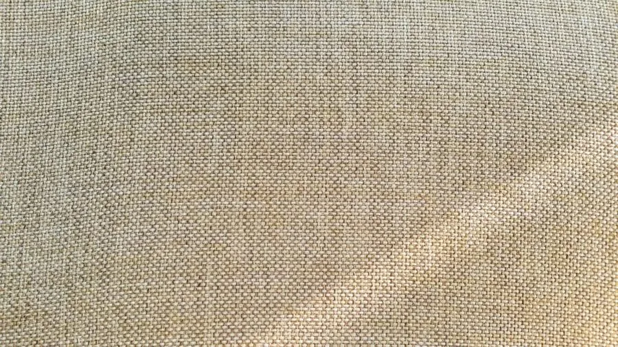 Person feeling and examining soft fabric texture on bed with natural lighting