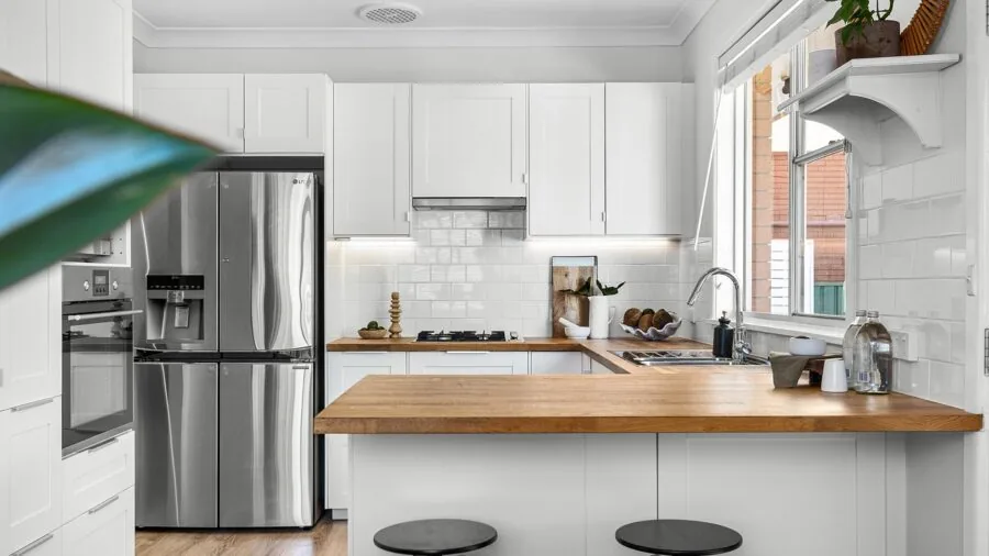 Person filling glass with water from refrigerator dispenser in contemporary kitchen