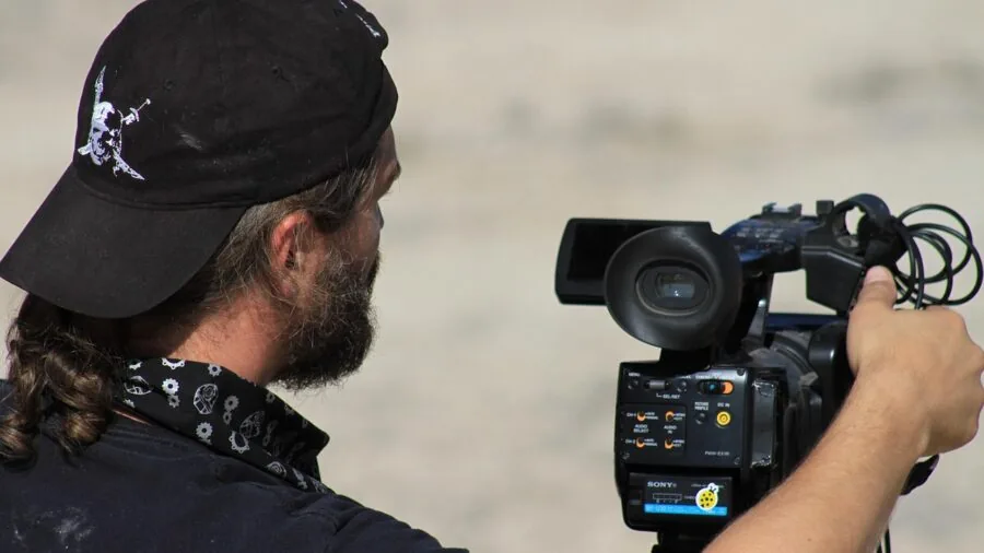 Person filming outdoor landscape with handheld camera, capturing natural scenery in bright daylight
