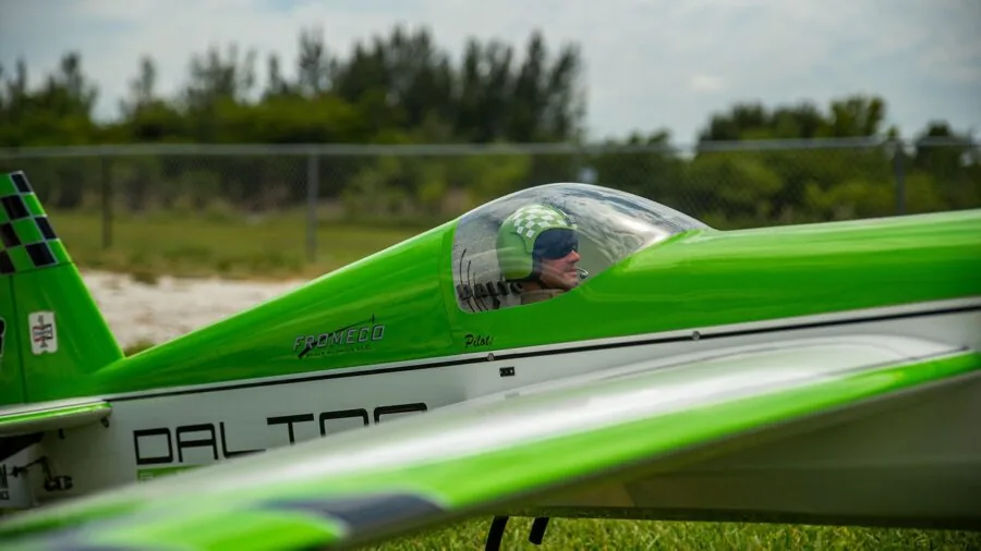 Person flying a foam RC plane in an open field on a sunny day