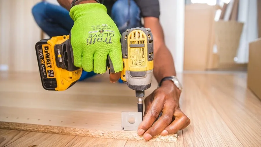 Person following assembly instructions while building furniture, focusing on instruction manual and tools