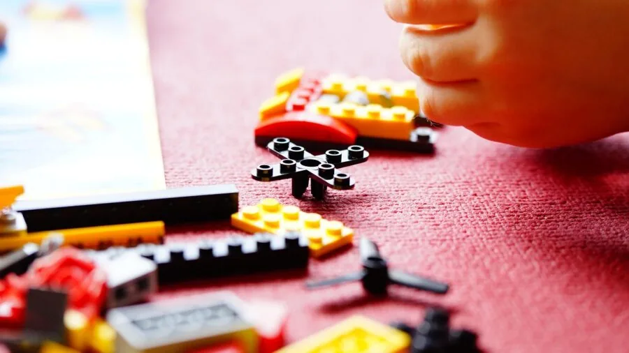 Person following step-by-step instructions while assembling a detailed model kit at a wooden workbench