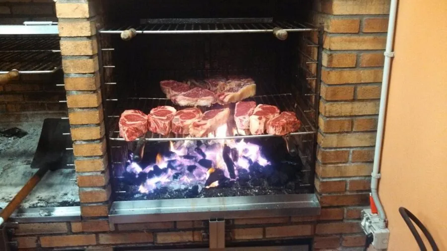 Person grilling food outdoors with visible heat and flames from gas grill