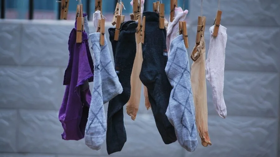 Person hand-washing socks in a basin of soapy water, demonstrating proper sock care and maintenance