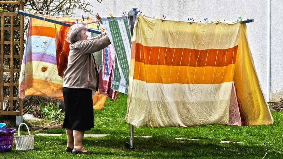 Person handling fresh clean white bedding during laundry day at home