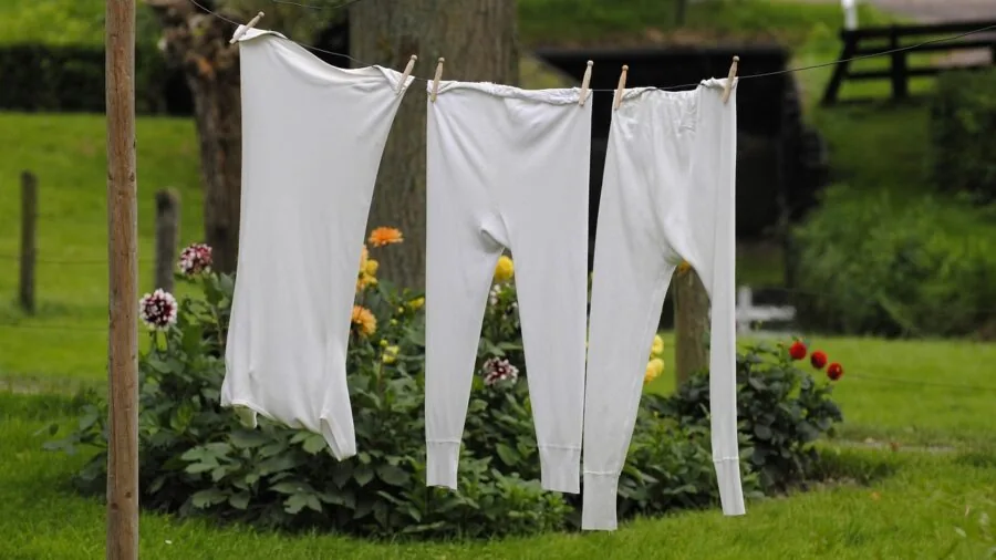 Person hanging wet clothes on line in shaded outdoor area to air dry naturally