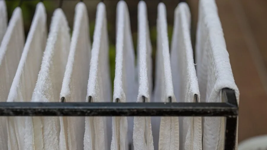 Person hanging wet towel in steamy bathroom after shower, demonstrating towel absorbency and drying time