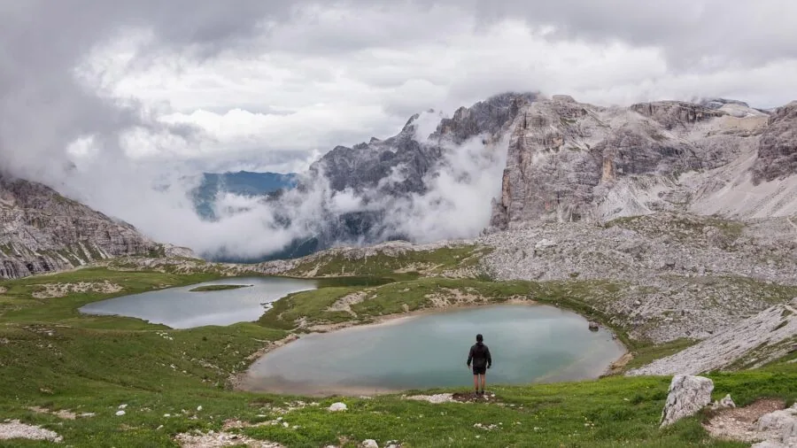 Person hiking on mountain trail wearing internal frame backpack with proper weight distribution