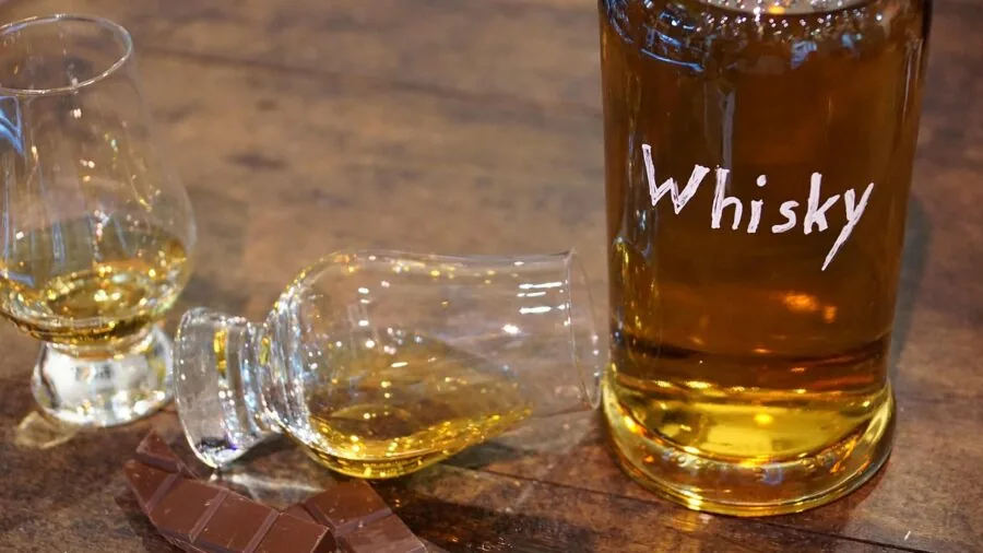 Person holding a weighted whiskey glass during an evening tasting session, demonstrating proper grip and balance