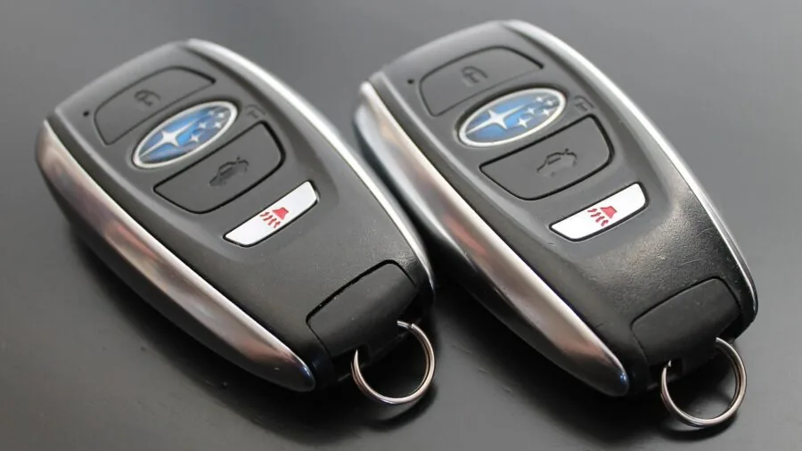 Person holding car key fob pressing button to unlock vehicle in parking lot