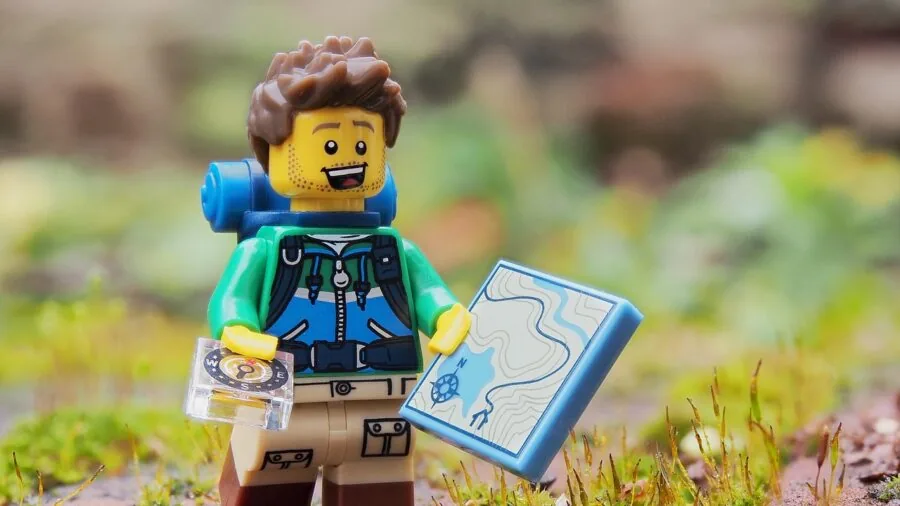 Person holding compass while hiking on a forest trail during daytime