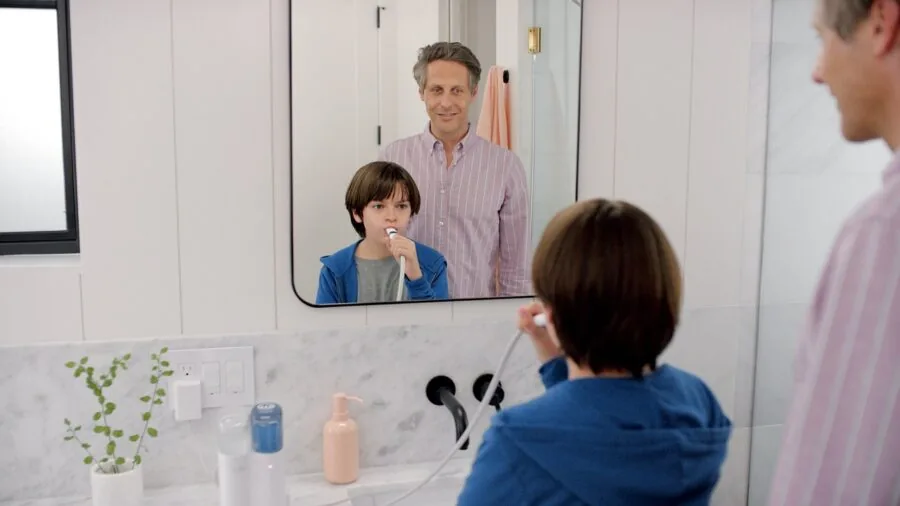 Person holding electric toothbrush in modern bathroom during morning grooming routine