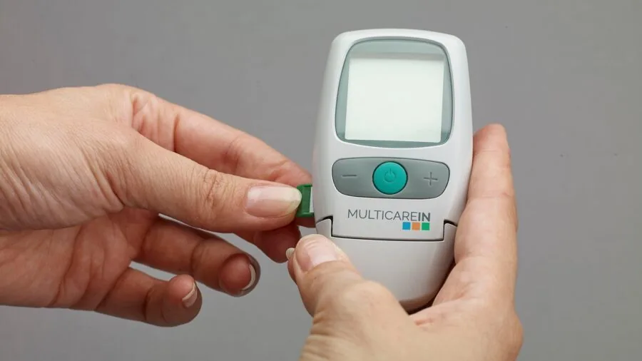 Person holding medical device with clear visible display screen in natural lighting