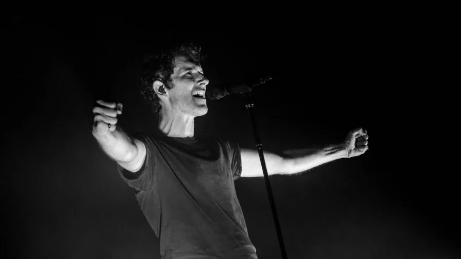 Person holding microphone singing passionately at home karaoke event with friends