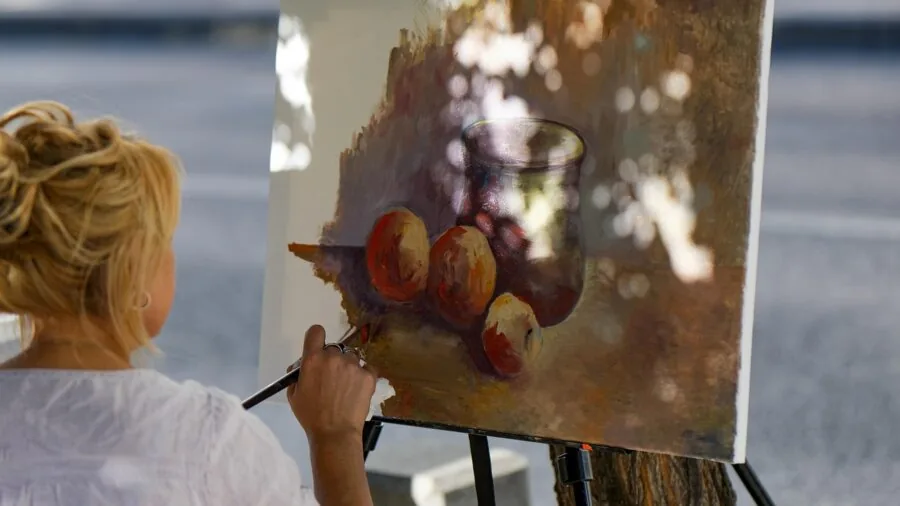 Person holding paintbrush while painting on canvas, demonstrating comfortable grip and hand positioning