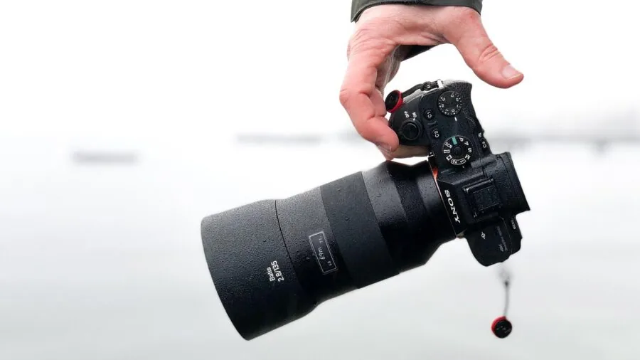 Person holding professional camera equipment while traveling outdoors in natural daylight