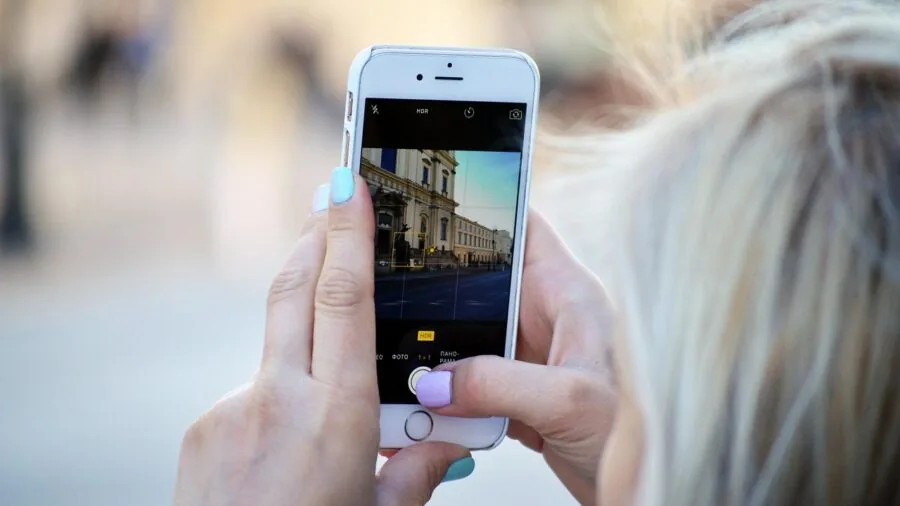 Person holding smartphone up to take a selfie or video outdoors in natural lighting