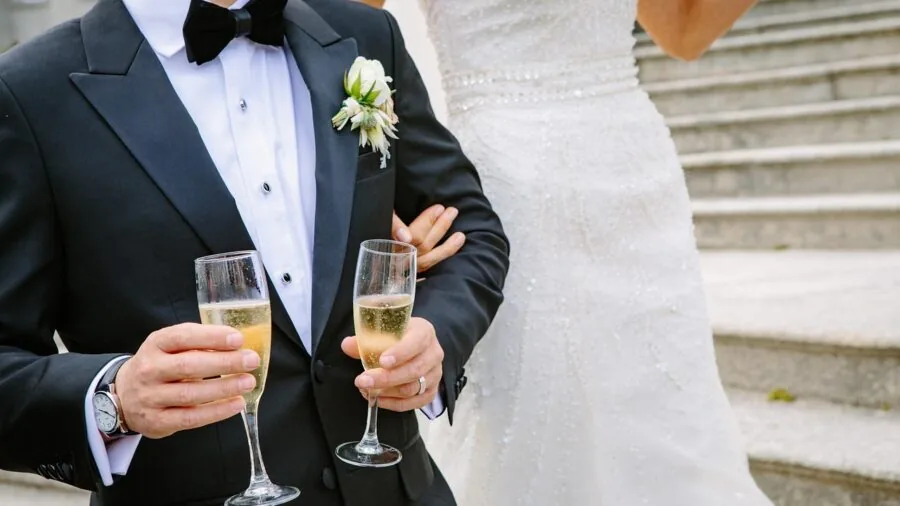 Person holding stemmed champagne flute by stem at elegant gathering