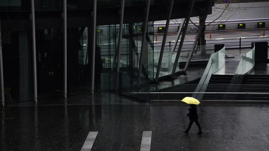 Person holding umbrella walking in rain, demonstrating weather protection and coverage in outdoor setting