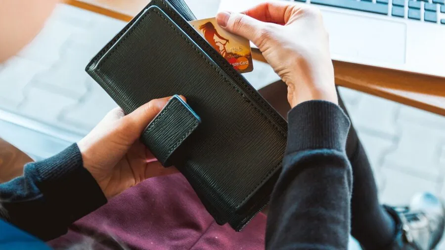 Person holding wallet with cards, illustrating financial security and protection of payment methods